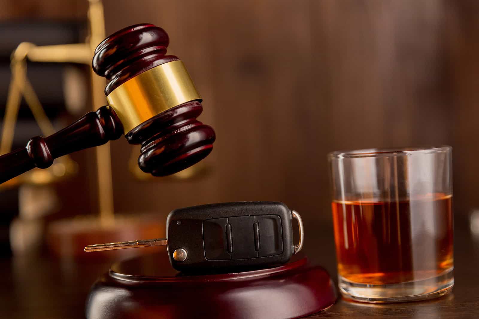 Gavel above car keys beside a glass of whiskey, representing DWI defense