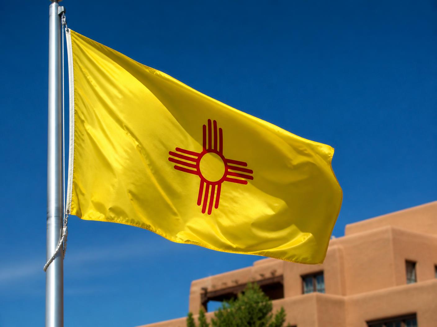 The New Mexico state flag with its red Zia symbol on a yellow field